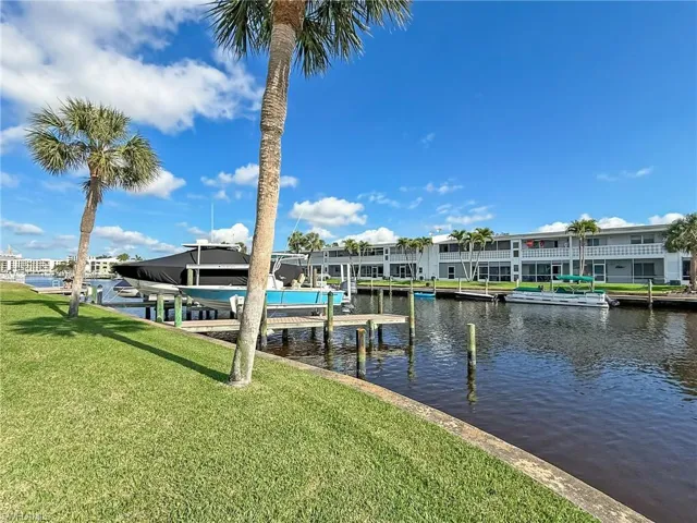 View of dock with a water view, boat lift, and a lawn