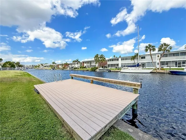 View of dock with a water view and a lawn