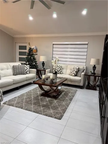 Living area with light tile patterned flooring, crown molding, ceiling fan, and recessed lighting