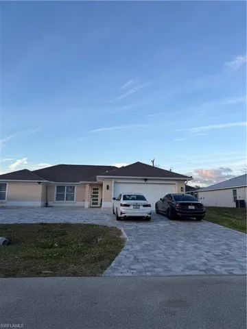 Ranch-style house with decorative driveway, a garage, and roof with shingles