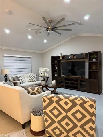 Living area with ornamental molding, light tile patterned flooring, vaulted ceiling, recessed lighting, and ceiling fan