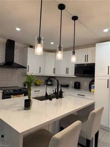 Kitchen featuring light stone counters, extractor fan, white cabinets, and recessed lighting