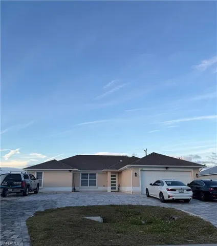 Ranch-style home featuring driveway, an attached garage, and roof with shingles