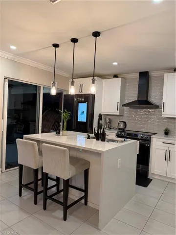 Kitchen with a kitchen island, range hood, crown molding, range, and decorative light fixtures