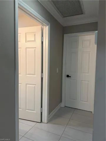 Corridor featuring light tile patterned floors and crown molding