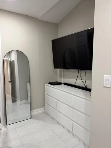 Unfurnished bedroom with light tile patterned flooring and arched walkways