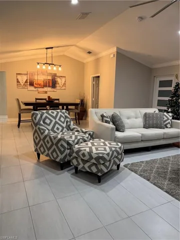 Living area featuring crown molding, vaulted ceiling, and tile patterned floors