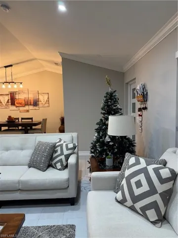 Living area featuring crown molding, vaulted ceiling, and light tile patterned floors
