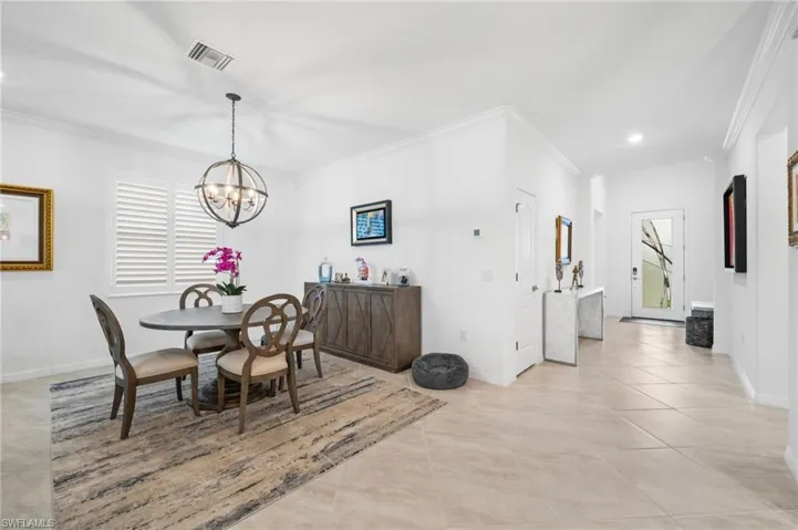 Tiled dining area with an inviting chandelier and crown molding