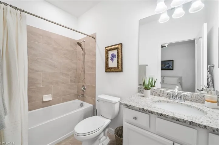 Full bathroom with shower / bath combination with curtain, vanity, and toilet