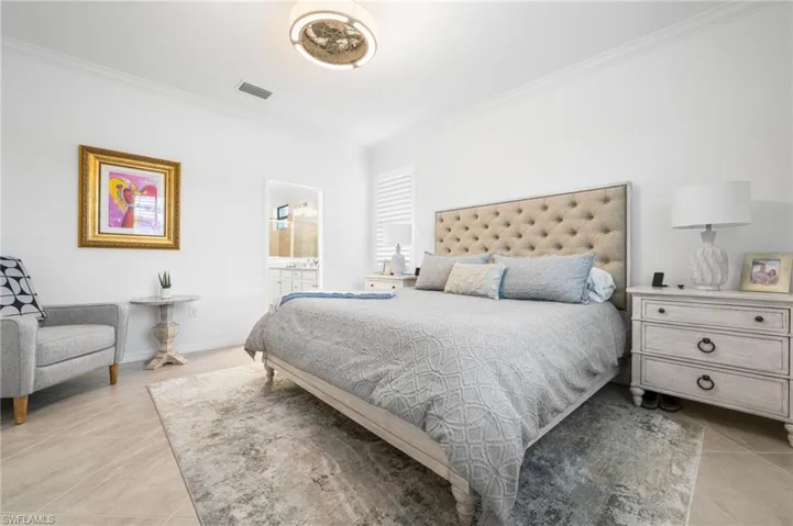 Tiled bedroom with connected bathroom and crown molding