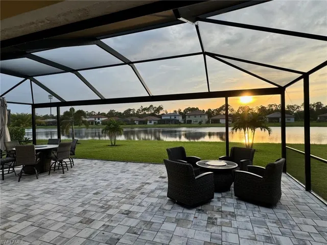 Patio terrace at dusk with a yard, a lanai, and a water view