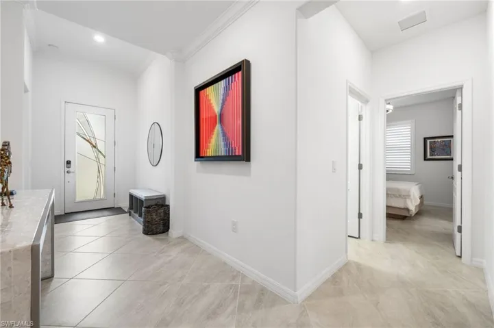 Hall with light tile patterned flooring and ornamental molding