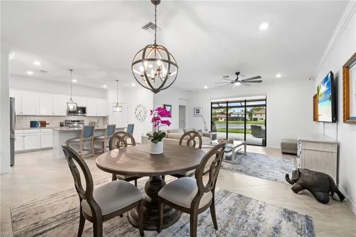 Tiled dining area with ceiling fan with notable chandelier and ornamental molding
