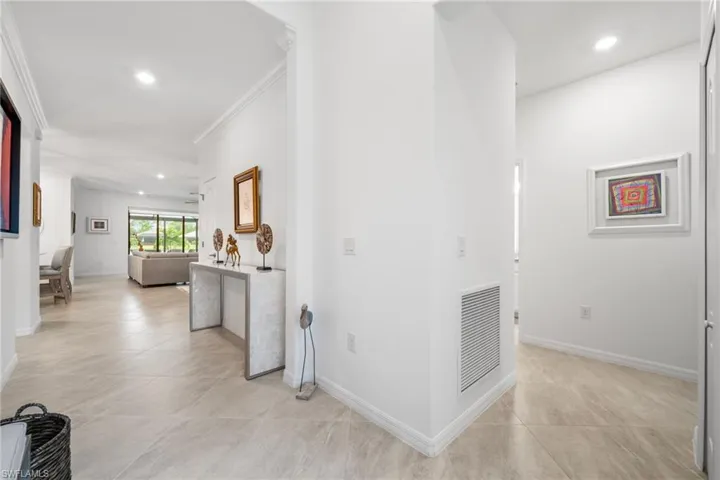 Hallway with light tile patterned flooring and ornamental molding