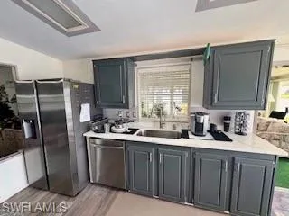 Kitchen featuring light countertops, appliances with stainless steel finishes, light wood-type flooring, and gray cabinets