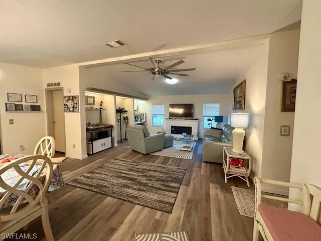 Living area featuring ceiling fan, a fireplace, and wood finished floors