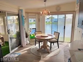 Dining room with wood finished floors, a water view, and a chandelier