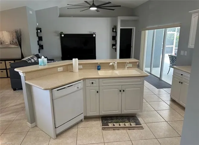 Kitchen with open floor plan, ceiling fan, dishwasher, and white cabinetry