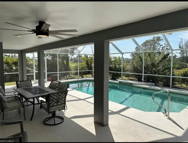 Outdoor pool featuring a patio area, outdoor dining space, glass enclosure, and a sunroom
