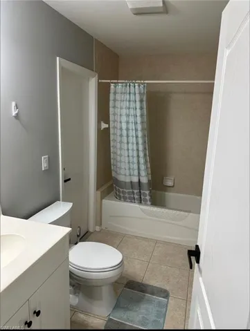 Full bathroom featuring vanity, shower / tub combo with curtain, and light tile patterned flooring