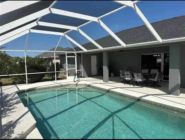 Swimming pool with glass enclosure, a sunroom, a patio area, and outdoor dining area