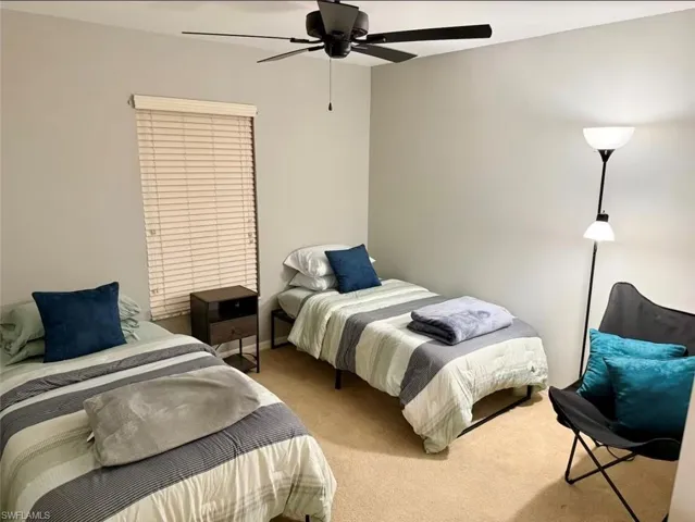 Carpeted bedroom featuring ceiling fan