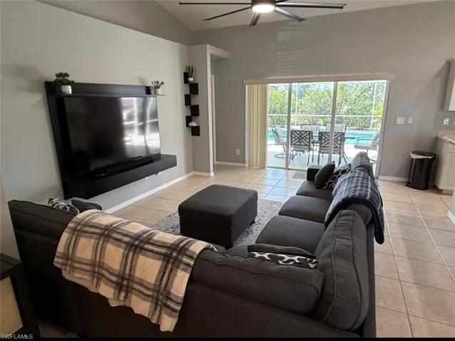 Living room with light tile patterned floors, a ceiling fan, and vaulted ceiling