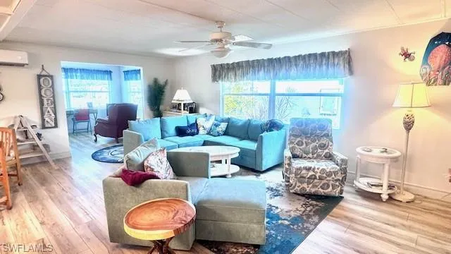 Living room featuring wood finished floors, plenty of natural light, ceiling fan, and a wall mounted AC
