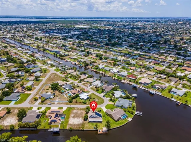 Aerial view of property and surrounding area featuring nearby suburban area and a large body of water