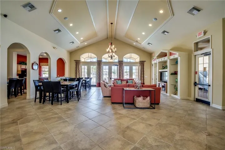 Living room with high vaulted ceiling, a chandelier, arched walkways, recessed lighting, and french doors