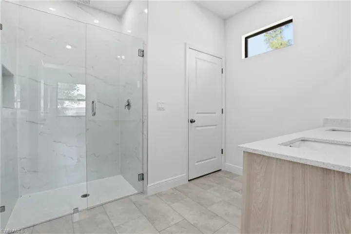 Bathroom with double vanity and a marble finish shower