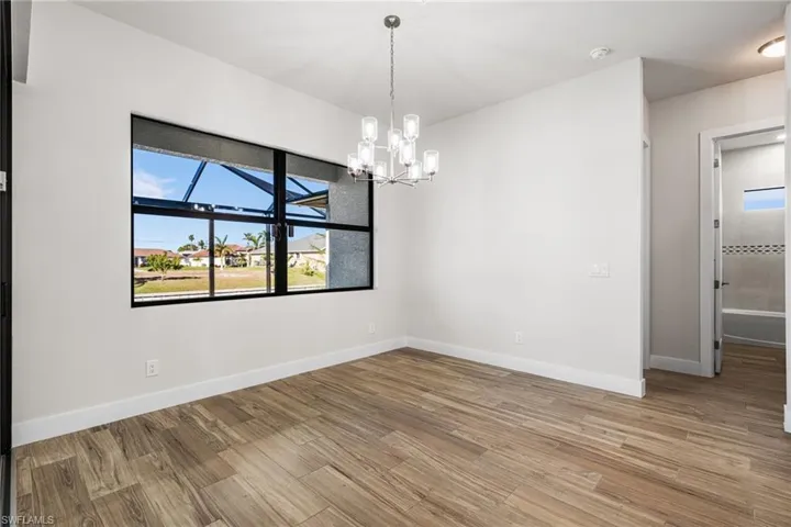 Unfurnished room with hardwood / wood-style flooring and an inviting chandelier