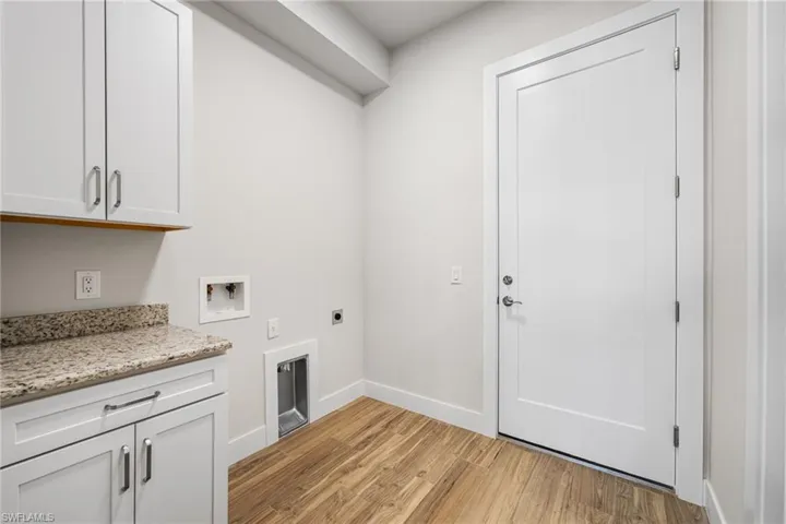 Laundry area with electric dryer hookup, light hardwood / wood-style flooring, cabinets, and washer hookup