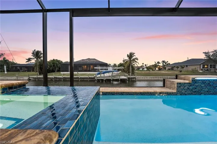 Pool at dusk featuring a water view