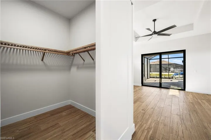 Spacious closet in primary bedroom featuring ceiling fan and wood-type flooring