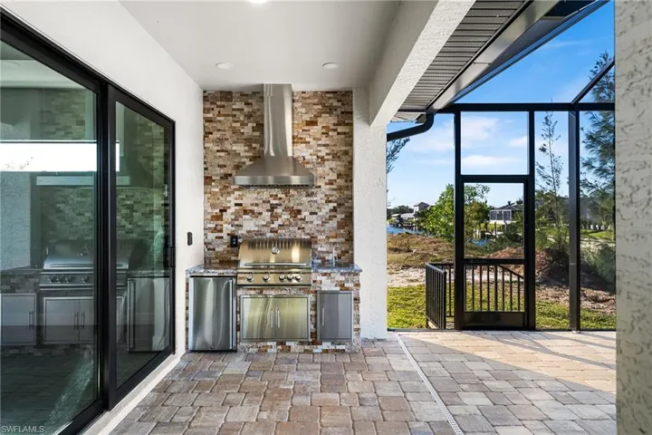 View of patio / terrace with a lanai, exterior kitchen, and grilling area