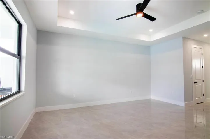 Empty room with ceiling fan and a raised ceiling