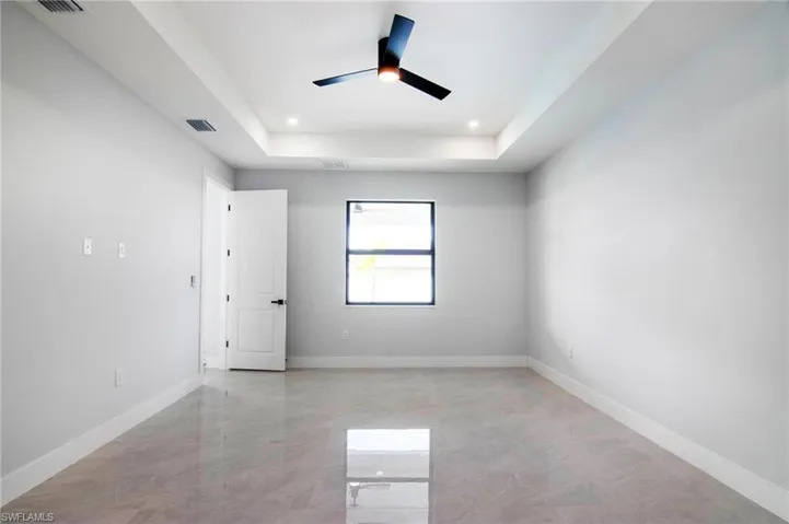 Unfurnished room with ceiling fan and a tray ceiling
