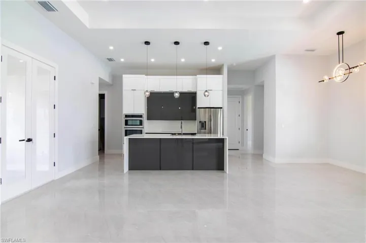 Kitchen with pendant lighting, white cabinets, a center island with sink, and stainless steel appliances