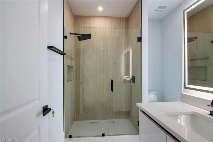 Bathroom with toilet, vanity, and an enclosed shower