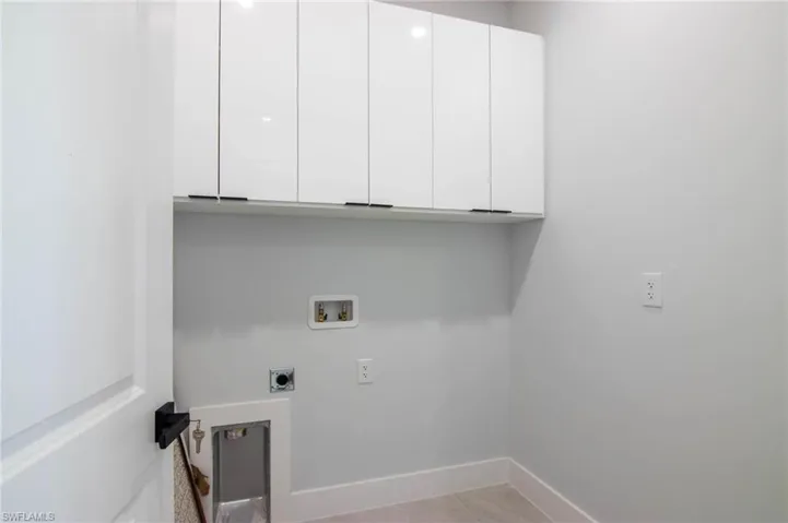 Laundry area featuring washer hookup, cabinets, light tile patterned floors, and electric dryer hookup