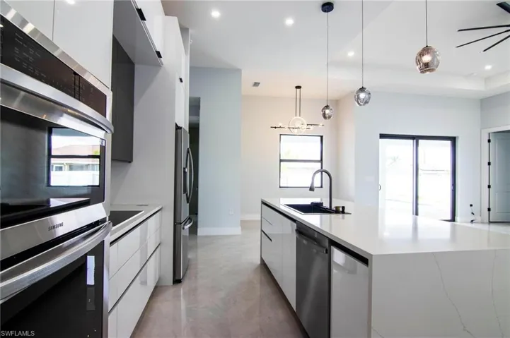 Kitchen with pendant lighting, white cabinets, appliances with stainless steel finishes, and sink
