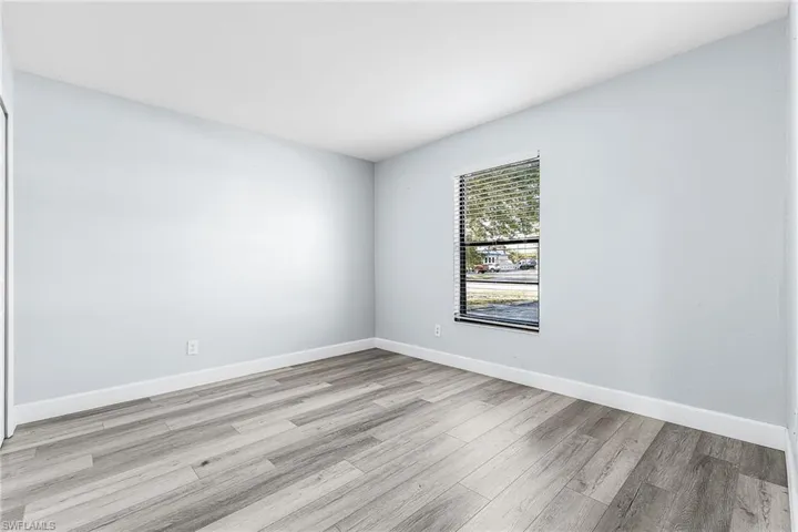 Room featuring wood-finish flooring, light-toned walls, and white baseboards