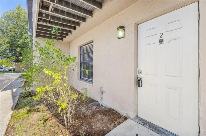 Entry door featuring a number plate and a wall-mounted outdoor light fixture