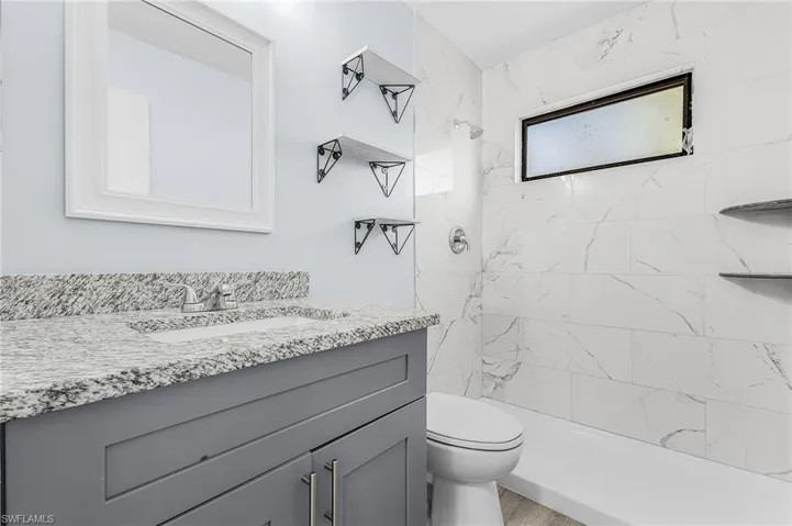 Bathroom featuring a gray vanity with a granite countertop, undermount sink, and chrome faucet