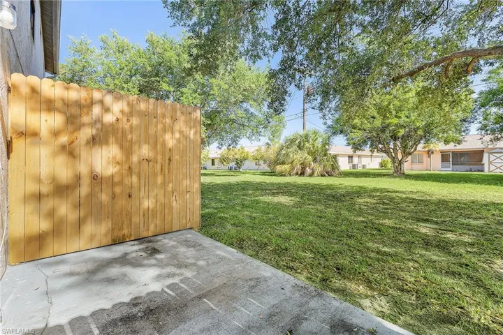 Outdoor concrete patio area with a natural wood privacy fence