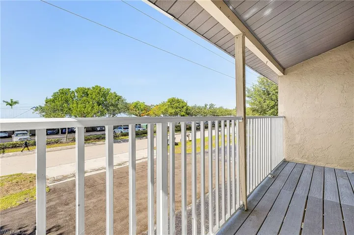 Outdoor balcony featuring plank flooring, a stucco exterior wall, and white railings