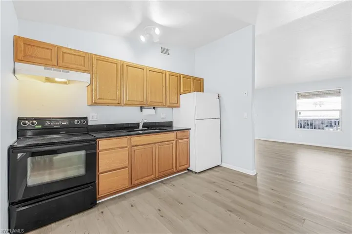 Kitchen area featuring wood cabinetry, black countertops, and a black range