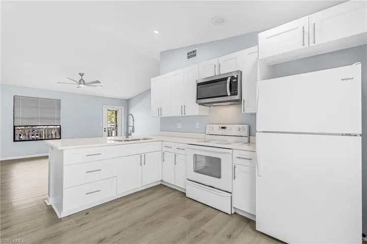 Kitchen featuring white shaker cabinetry, light-toned countertops, and a full suite of appliances